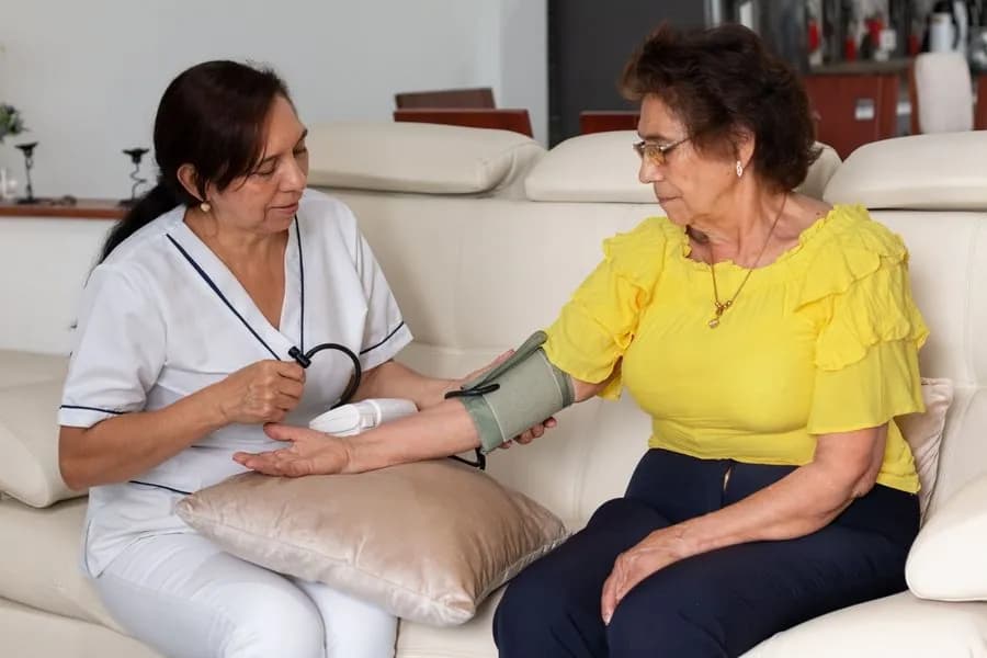 Enfermera tomando la presión a una señora mayor en su casa
